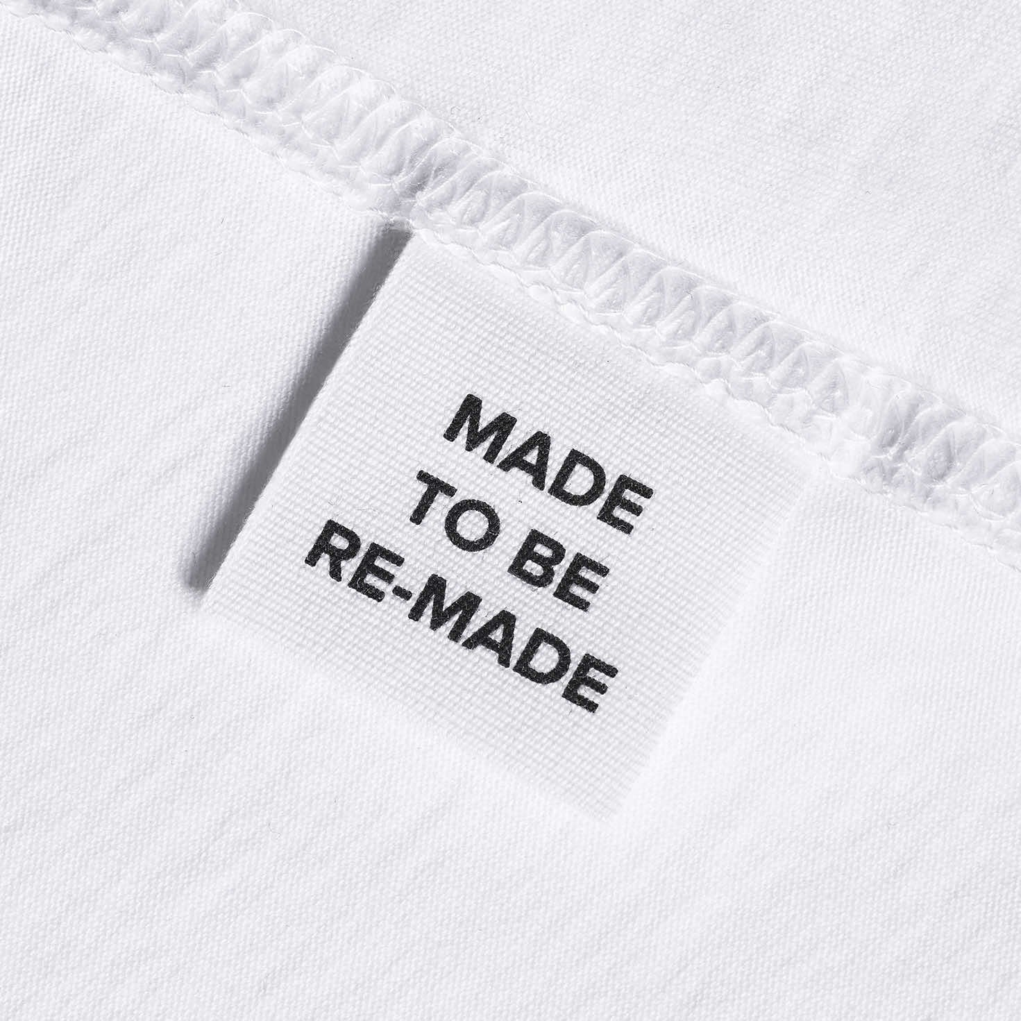 A close up of a label tag in a white organic cotton t shirt that says 'made to be re made'.